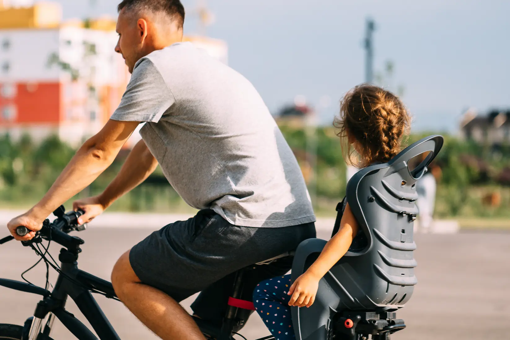 Father cycling with his daughter in a child carrier seat